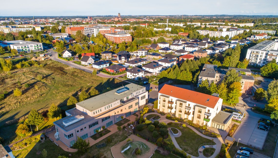 Eine Drohnenaufnahme der Kita Siebenschl&auml;fer. Im Hintergrund ist Wismar zu sehen.