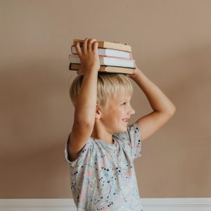 Zwei Mädchen halten aus Spaß je einen Stapel Bücher über den Kopf.