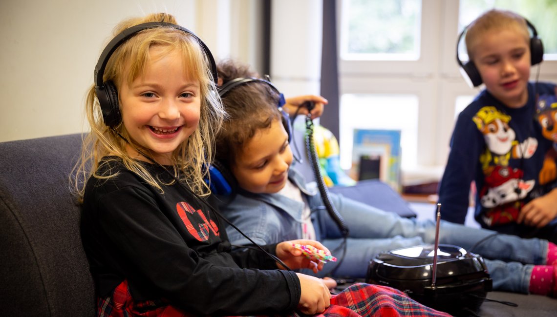 3 Kinder h&ouml;ren mit Kopfh&ouml;rern Musik.