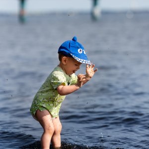 Ein kleiner Junge spielt im Meer. Das Wasser geht ihm bis zu den Kn&ouml;cheln.