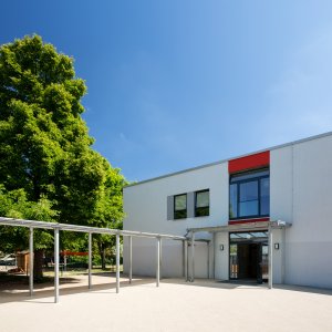 Der Eingangsbereich vom Hort Sonnenschein mit dem gro&szlig;en gr&uuml;nen Laubbaum daneben