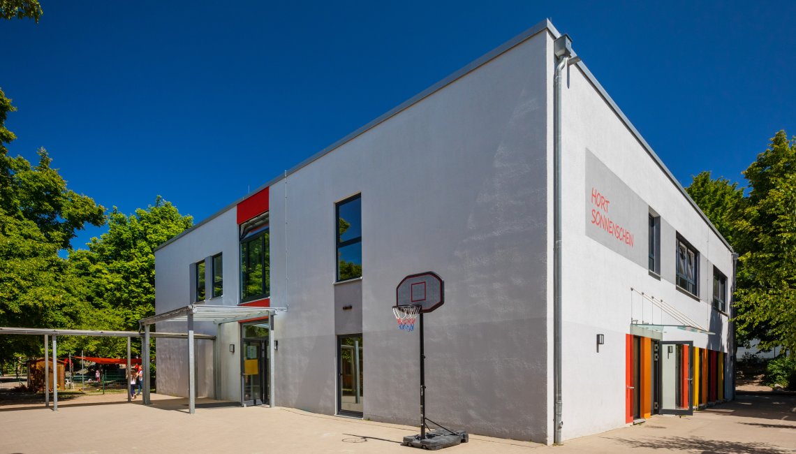 Eine Au&szlig;enaufnahme des Hort Sonnenschein. Im Vordergrund ist ein Basketballkorb.