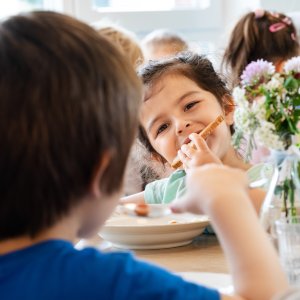 Ein M&auml;dchen bei&szlig;t von einem Brot ab.